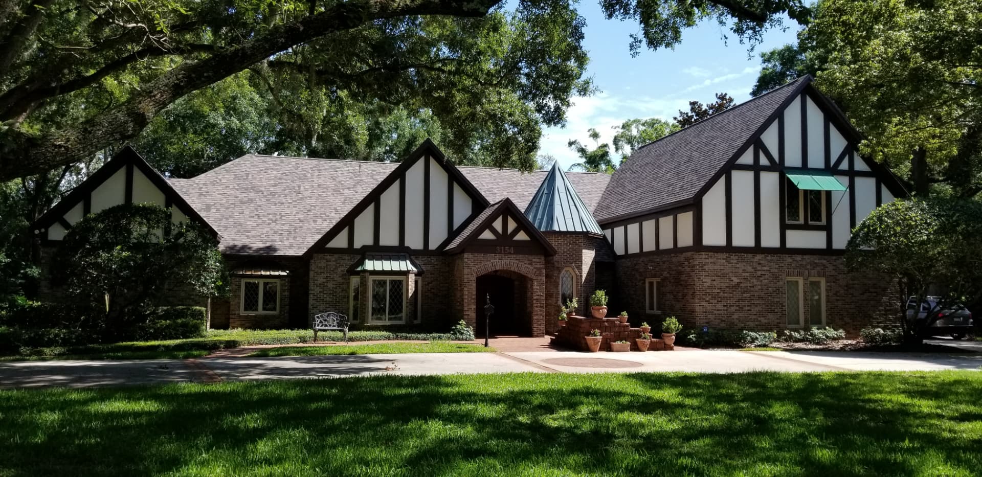 Repainted Tudor-style brick home with fresh dark trim and cream stucco panels